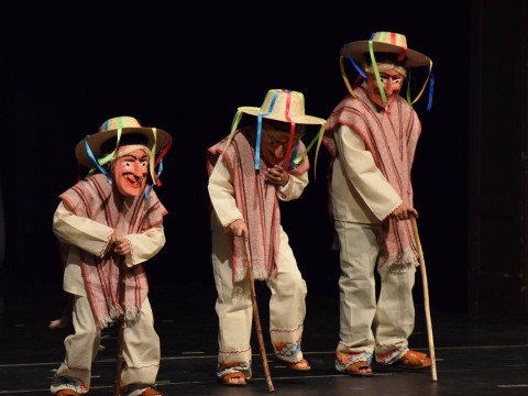 Three boys in traditional masks on stage.